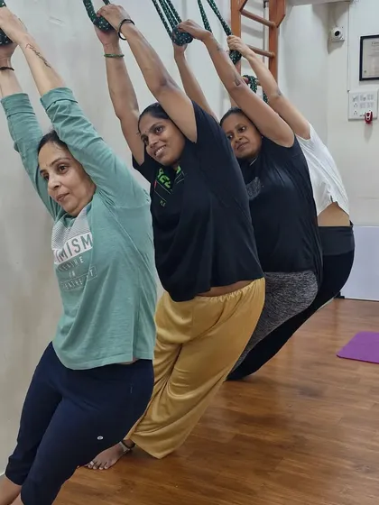 Students hang from the rope wall, a practice that helps decompress the spine and relieve tension. It's a therapeutic and invigorating part of our props yoga sessions.