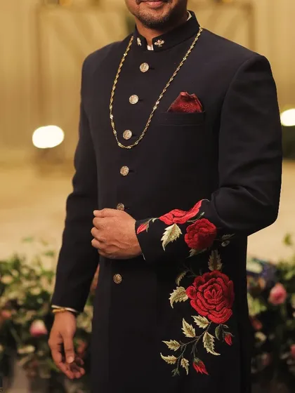 A partial view of the sherwani, showing the gold chain, pocket square, and embroidered sleeve. Each element comes together to create a cohesive and luxurious look.
