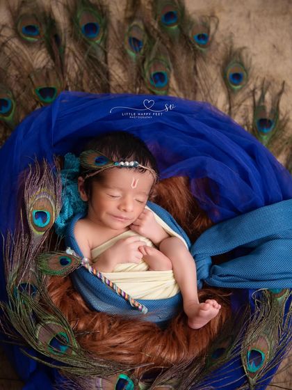 Our little Krishna, surrounded by the iconic peacock feathers. I use rich colors and textures, like the deep blues and soft furs, to create a divine and peaceful setting for your baby.