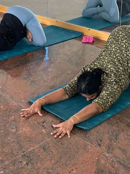 Another angle of our students in a preparatory stretch. The use of the mirror helps in self-correcting alignment and deepening the mind-body connection.
