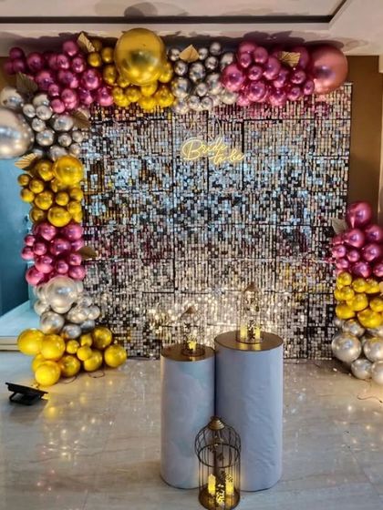A glamorous sequin wall with a balloon arch in magenta, gold, and silver.