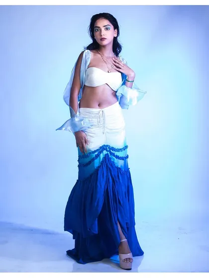 A full-length shot capturing an ethereal, water-inspired theme. The gradient blue of the skirt and the sheer, airy sleeves are highlighted by the cool-toned lighting, creating a cohesive, mermaid-like aesthetic.