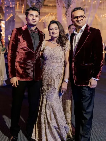 Creating unforgettable moments starts with impeccable style. For this cocktail soirée, we dressed the family in a coordinated palette of rich burgundy velvet and shimmering gold. The mother of the groom looks radiant in a Tarun Tahiliani gown, standing with her elegantly dressed husband and son.