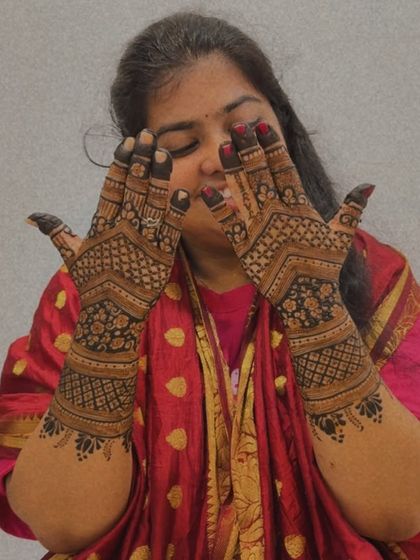 A candid moment of a guest admiring her freshly applied, detailed henna design.
