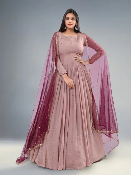 A beautiful dusty pink gown with a sheer maroon dupatta. The simple silhouette and elegant color make it a versatile choice.