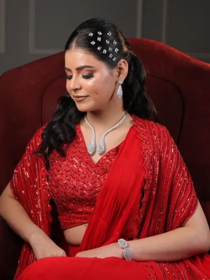 Another beautiful shot of the red saree look. Her elegant pose in the chair highlights the intricate hairstyle and the flawless makeup.