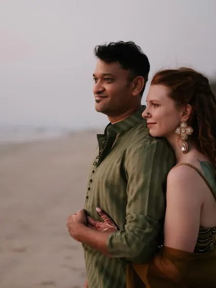 A serene portrait of the couple against the ocean backdrop. Their relaxed, nature-inspired outfits were designed to feel both special and completely at ease.