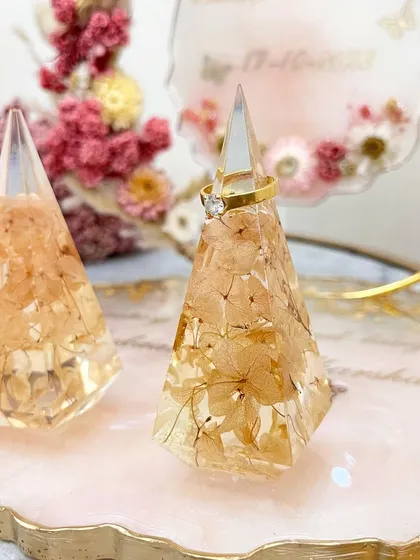 A detailed shot of the custom pyramid ring holders, showing the preserved flowers inside.