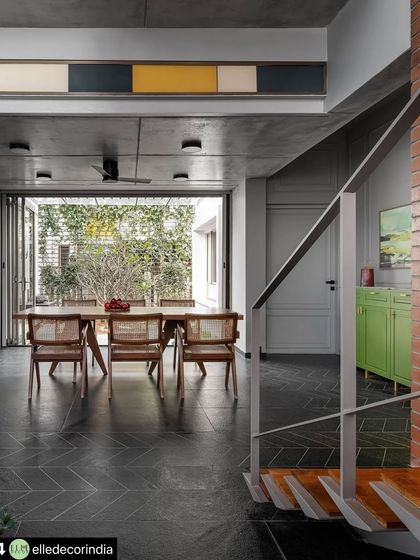 From this angle, you can see the interplay of materials and sightlines. The metal staircase railing frames the view into the dining room, which opens directly to the garden, highlighting the home's continuous flow between spaces.