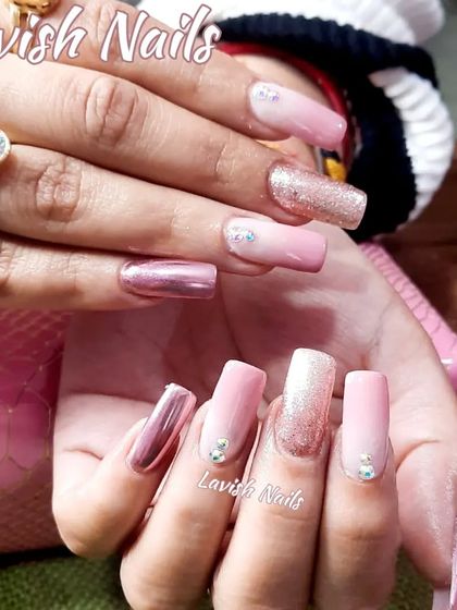 A glamorous set of long square nails with a mix of chrome pink, pink ombre, glitter, and rhinestone accents.