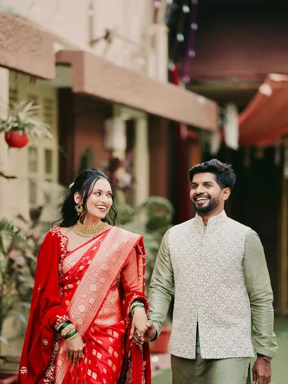 A beautiful couple shot capturing their happiness. The bride's look in a traditional red saree is timeless, with makeup that enhances her features without overpowering them.