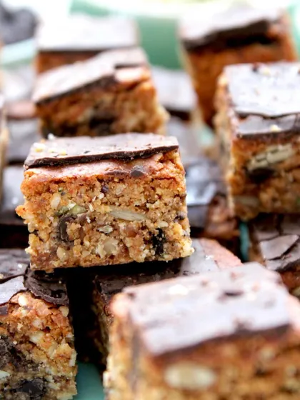 A close-up of my protein-rich Energy Bars. I pack them with oats, hemp seeds, and a mix of nuts, then top them with a thin layer of dark chocolate. They are the perfect snack for a midday energy boost.
