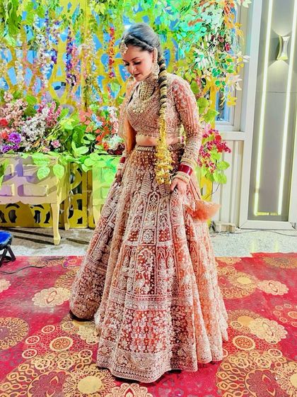 A detailed shot of the intricate embroidery on the red and gold bridal lehenga. Every panel tells a story, making this rental a piece of art for your wedding day.