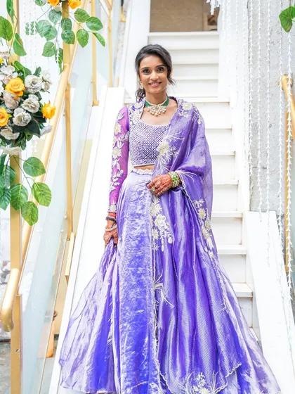 A full-length shot of this client for her Siddhi Tap ceremony. She looks serene and elegant in a beautiful purple lehenga, with makeup that enhances her natural grace.