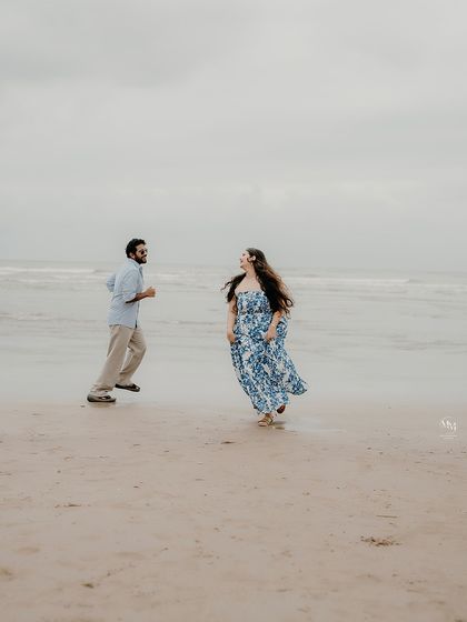 A wide shot of the couple running and laughing on the beach, capturing their free-spirited nature against the vast ocean backdrop.