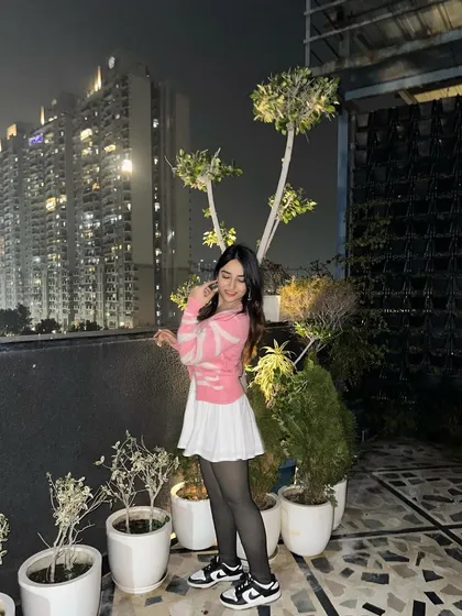A smiling pose in the pink cardigan outfit. The rooftop setting with city lights is one of my favorite backdrops.