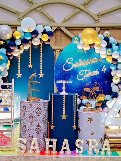 A "Twinkle Twinkle Little Star" themed fourth birthday. The deep blue and gold decor features star-themed plinths, a galaxy backdrop, and a large light-up number '4'.