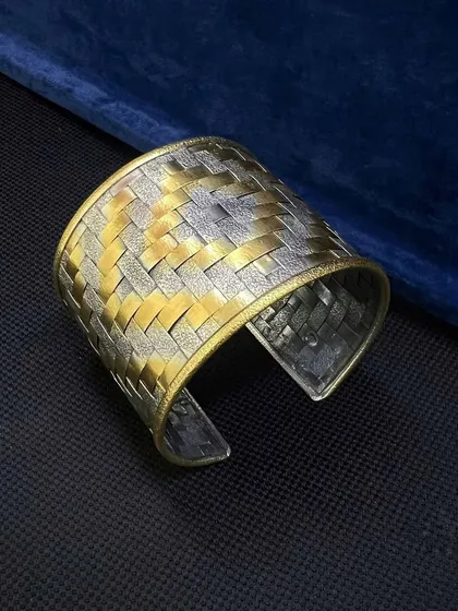 A third look at the dual-tone woven cuff, highlighting its substantial feel and the way the light catches the different metallic textures.