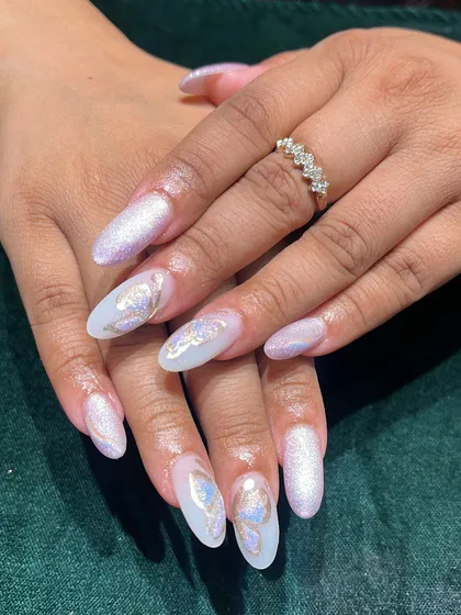 This is what we mean by nails that tell a story. This dreamy look features long almond-shaped acrylic extensions with a pearlescent base, topped with delicate, holographic butterfly art. It's a perfect example of our custom, high-end nail design.