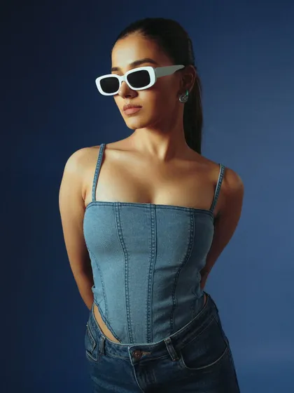 A simple, chic portrait focusing on a denim corset top. The clean styling and solid blue background make this a perfect e-commerce shot that is both stylish and informative.