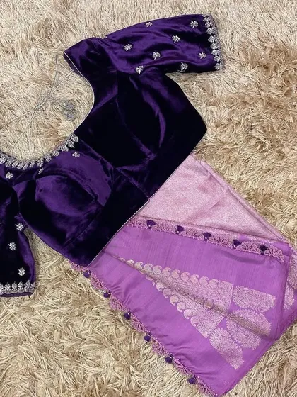 A luxurious velvet blouse in a deep violet shade, adorned with silver hand embroidery. This piece is paired with a lavender silk saree for an elegant, monochromatic look.