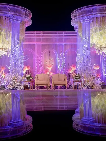 A closer look at the reception stage, flanked by two large pillars made of the same crystal-like mesh and filled with cascading florals. The design is both grand in scale and intricate in detail.