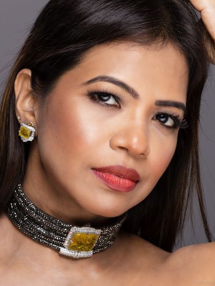 A close-up beauty shot highlighting a statement choker with a large yellow gemstone. The focus is on the intricate details of the jewellery piece.