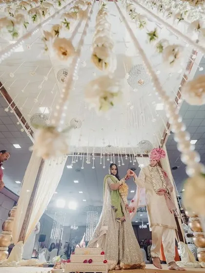An upward-looking shot of an indoor mandap, where strings of white flowers and pearls create a celestial, dreamy canopy for the couple's vows.
