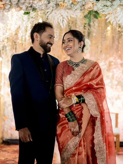 A classic reception look with an elegant royal touch. The bride's radiant glow and stunning silk saree are perfect for her special evening, seen here sharing a laugh with her husband.