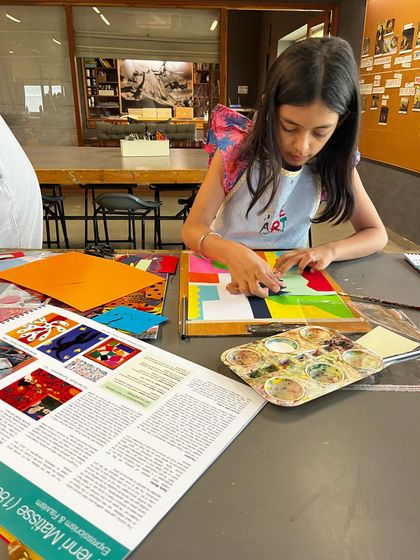 A student works on a colorful collage, learning about the art of Henri Matisse.
