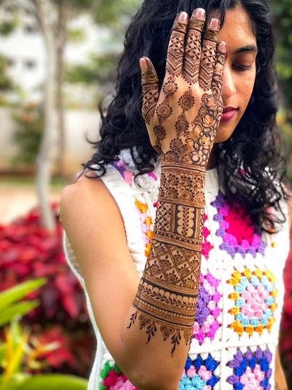 A stylish pose showing off a full arm of henna, with a mix of geometric and mandala-inspired patterns.