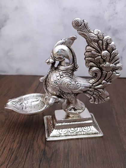 My antique German silver peacock diya is a work of art. The peacock, with its detailed feathers and form, holds the lamp, making it a symbol of grace and divinity.