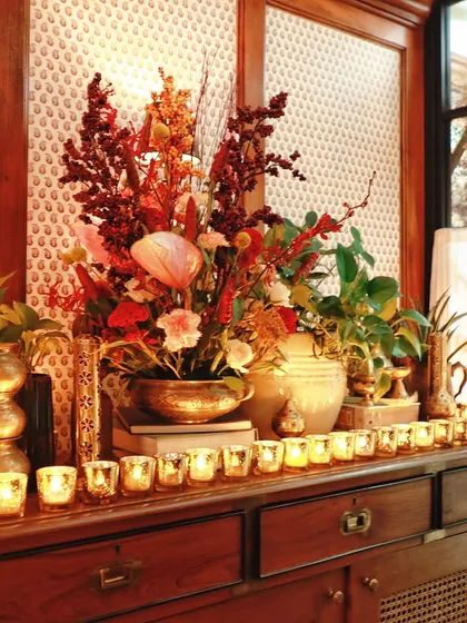 A beautifully styled console table with candles, books, and a floral arrangement in a brass bowl.