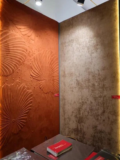 A view of our exhibition booth, featuring a bold, orange 3D wallcovering alongside a more subtle, textured design. This showcases the range and versatility of our collections.