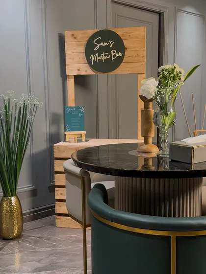 A custom "Martini Bar" we built for a birthday party. The rustic wooden stand, combined with a modern sign and simple floral arrangement, created a dedicated and stylish space for drinks.