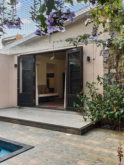 A private villa with its own plunge pool, surrounded by flowering vines and tropical plants. The open doors invite a seamless flow between the indoor space and the private outdoor oasis.