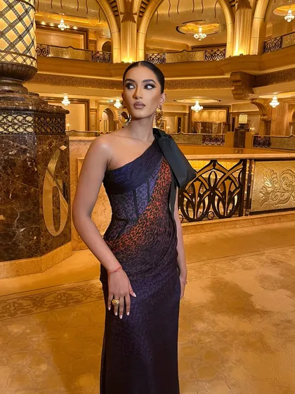 A side profile that highlights the structure of the gown and the elegance of the sleek hairstyle.
