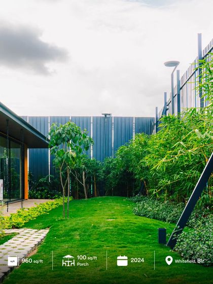 This wide shot captures the full context of the 960 sq.ft. modular office in Whitefield, Bangalore, showing its relationship to the surrounding landscape and boundary. The project includes a 100 sq.ft. porch for a complete indoor-outdoor experience.