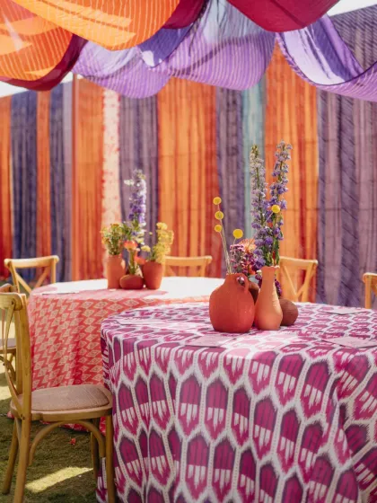 A riot of color and pattern with custom ikat-print tablecloths and vibrant floral centerpieces. We use textiles to build layers of visual interest and tie a theme together.