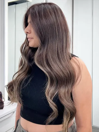 A beautiful signature balayage with soft, flowing waves. The highlights are strategically placed to create a look that is both striking and natural.