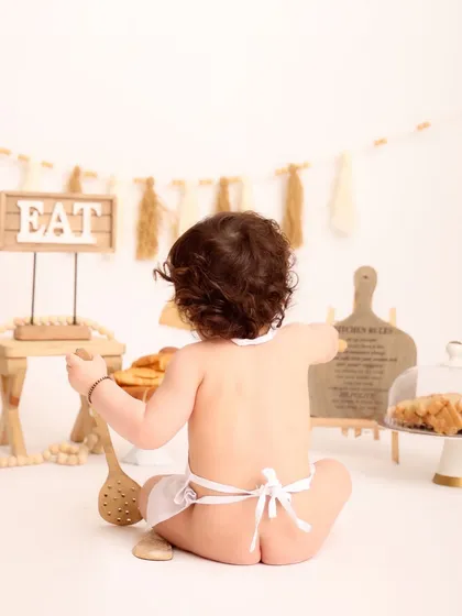 A cheeky and adorable shot from behind, showing the baby chef in his apron. This photo adds a playful and unexpected element to the collection.