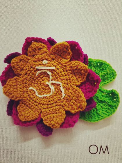 A spiritual and serene crochet piece featuring the 'Om' symbol on a lotus flower. This makes a beautiful wall hanging or a centerpiece for a meditation space.