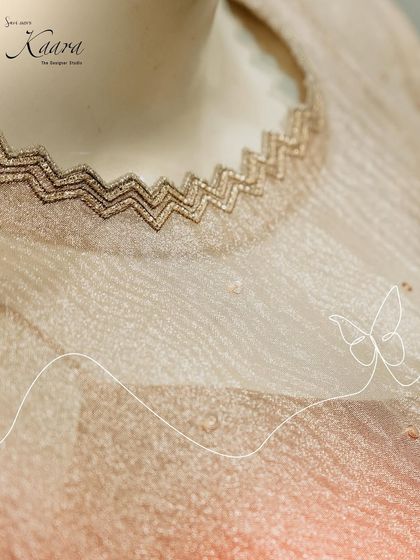 A macro shot of the delicate chevron-patterned embroidery on the neckline of our net kurti. This detail adds a touch of modern geometry to the otherwise soft and shimmering fabric.
