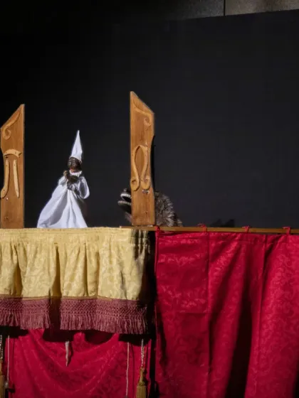 A scene from 'Io, Pulcinella' featuring the main character and a mysterious animal puppet, adding to the comedic and surreal nature of the show.