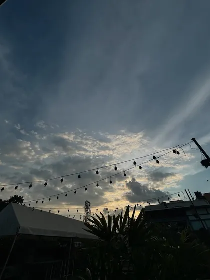 The beautiful evening sky over our rooftop venue, with string lights silhouetted against the clouds, promising a magical night ahead.