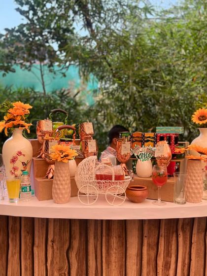A wide shot of a sunflower-themed bar for a daytime event. The bar front has a natural wood finish, and the counter is decorated with bright yellow sunflowers in various vases.