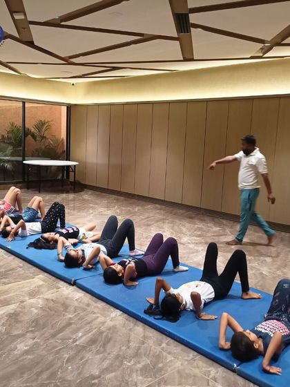 Students lie on mats preparing for a core workout. Building core strength is a fundamental aspect of our fitness programs for all age groups.