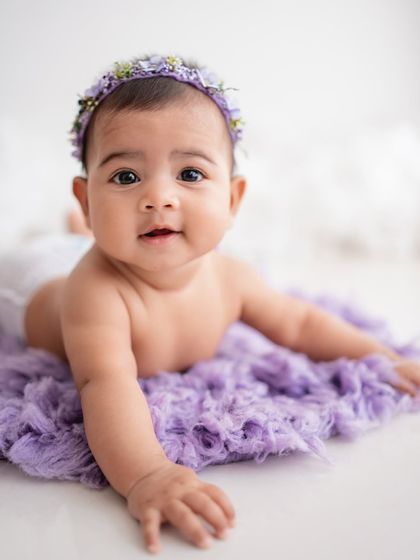 A simple and sweet portrait of a baby girl on a purple blanket.