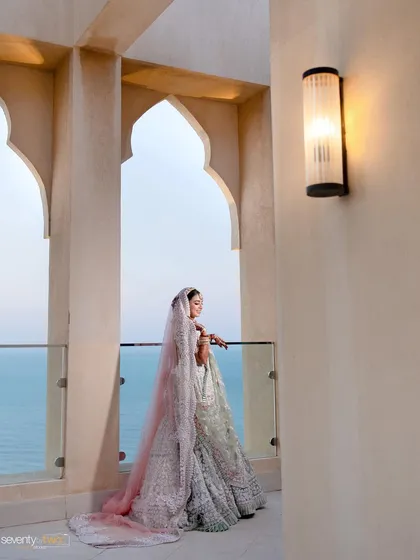 A bride gazes out at the ocean from her balcony at the Waldorf Astoria in Dubai, a moment of quiet contemplation before her grand wedding.