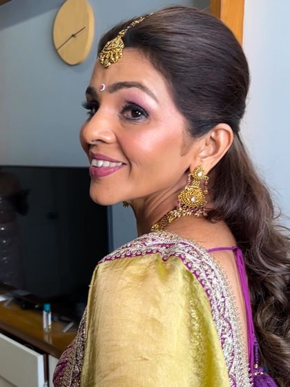 A side profile highlighting the soft, blended eyeshadow and the elegant hairstyle. This shows how the complete look comes together, from the makeup to the hair and traditional jewelry.